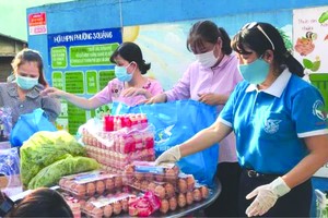 第六郡婦聯會主席梁氏菁竹(右一) 親自給隔離居民派發應用品。