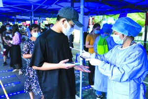 在南京市北門橋社區核酸檢測點，工作人員在用手機掃描市民身份證信息。