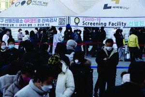 人們在韓國首爾江南區一處新冠檢測點排隊等待核酸採樣。