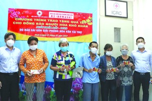 第五郡人委會副主席阮武春奇(左)、本報 編委文忠孝(右)向華人同胞贈送禮物代金。