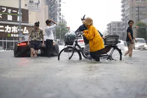 Người dân băng qua một con đường ngập lụt ở Nagoya (Ảnh: THX)