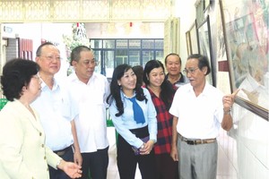 李松年書法家(右一)向參與者介紹陳列的書畫。