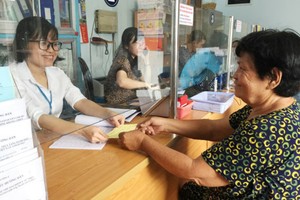 陳氏紅詩熱情地指引現年72歲的阮氏珊辦理申請領取殘疾人士福利卷宗。資料圖：SGGP