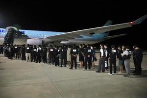 10月18日凌晨，在柬埔寨金边德崇国际机场，警察押送被遣返的韩国网络诈骗嫌疑人登机。