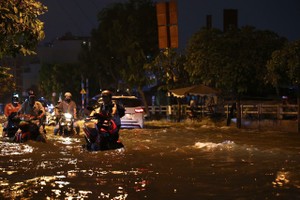 胡志明市新顺坊陈春撰街潮汛仍高涨，河水涌入民房，导致交通堵塞 。