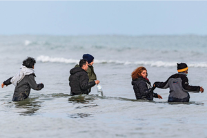 2024年4月26日，在法国北部敦刻尔克附近的格拉沃利讷海滩，移民走进大海准备乘橡皮舟渡海前往英国。