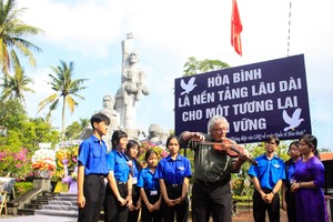来自Madison Quakers组织的迈克·伯姆在山美纪念碑下演奏小提琴，以“美莱的小提琴声”为主题缅怀遇难者。