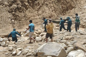 雄山乡民兵力量用吊床抬着病人越过塌方区域。