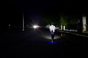 7月10日，在古巴首都哈瓦那，一名男子骑滑板车驶过漆黑的街道。