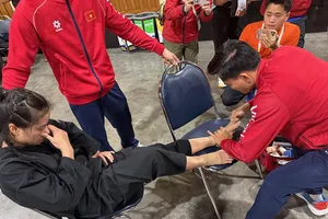 Nhân viên y tế Lê Viết Lãm giúp võ sĩ pencak silat vượt qua cơn đau sau khi vừa thi đấu trận chung kết. Ảnh: MINH CHIẾN