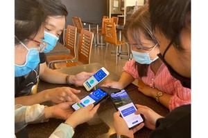 Young people are helping one another to install Bluezone app on their smart devices. (Photo: SGGP)