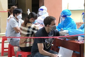 Wesly (in black T-shirt, from Canada) is having his health checked after being vaccinated. (Photo: SGGP)