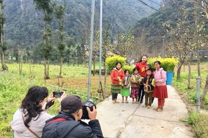 HCMC tourists are taking pictures of children in Lung Cam Cultural Tourism Village in Ha Giang Province. (Photo: SGGP) 