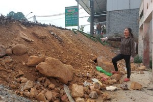 Tran Thi Thanh from Tan Tien Village of Phu Loc Commune is standing in front of her house, which is much lower than the newly upgraded road section. (Photo: SGGP)