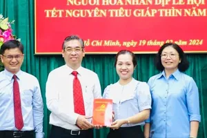 Deputy Secretary Nguyen Phuoc Loc of the HCMC Party Committee is delivering financial aid to the Social Welfare and Study Promotion Fund of District 5 (Photo: SGGP)