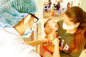 A medical employee at Tan Binh District Health Clinic (HCMC) is injecting vaccine to a child (Photo: SGGP)