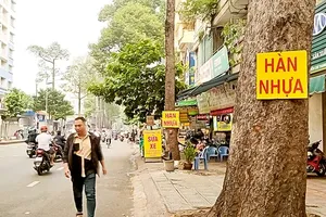 Trees on Nguyen Chi Thanh Street in District 5 are attached with illegal advertisements