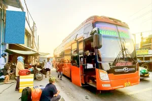 A coach is illegally picking up passengers at a makeshift station on National Highway No1A passing the Go May Overpass in Binh Tan District 