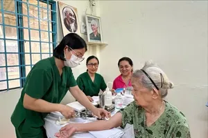 A healthcare worker is taking a blood sample from an older resident of Xuan Hoa Ward during a health screening