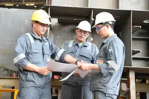 Engineer Nguyen Van Loc (on the left) is discussing technical matters with his colleagues during working time (Photo: SGGP)