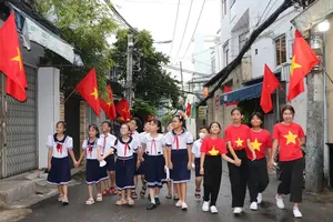 Students in Xom Chieu Ward of HCMC are joyfully walking along a street lined with national flags (Photo: SGGP)