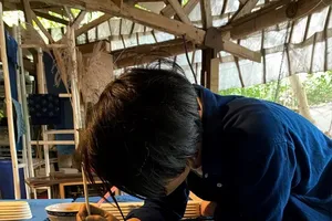 An incredibly focused artisan is painting directly onto the silk fabric strictly following the manual indigo dyeing process (Photo: Do Do Lamp shop)