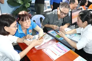 Members of the Binh Quoi Ward digital neighborhood team are guiding an elderly citizen on properly utilizing mobile phone applications right inside the residential area (Photo: SGGP)