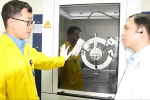 Nguyen Trong Nghia, MSc, from the Nano and Material Analysis Department at HCMBiotech (left) is standing beside the X-ray Diffraction (XRD) equipment (Photo: SGGP)