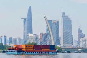 A heavy container barge navigates the Saigon River, drifting past the Ba Son Bridge area, actively contributing to HCMC’s vibrant commercial rhythm (Photo: SGGP/Hoang Hung)