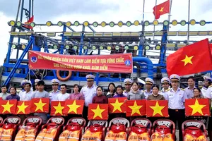 Tặng cờ Tổ quốc, áo phao, phao cứu sinh, túi y tế cho ngư dân tại cảng cá Bình Châu. Ảnh: THÀNH HUY