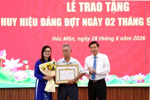 Đồng chí Trần Văn Tuấn - Ủy viên Ban Thường vụ Thành ủy, Trưởng Ban Nội chính Thành ủy TPHCM và Bí thư Đảng ủy xã Hóc Môn Lê Thị Ngọc Thanh trao Huy hiệu 55 năm tuổi Đảng đến đảng viên lão thành. Ảnh: NGÔ BÌNH