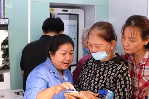 Hướng dẫn người cao tuổi cài đặt các ứng dụng tại Trạm Công dân số. Ảnh: HỒNG HẢI