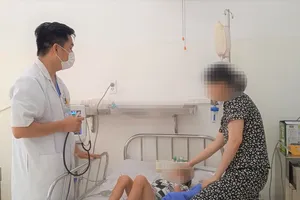 Bác sỹ Nguyễn Hải Thịnh đang khám bệnh cho con của chị Lê Thị Ngọc Châu. Ảnh: XUÂN QUỲNH