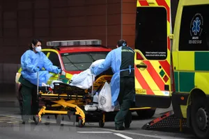 Nhân viên y tế chuyển bệnh nhân Covid-19 tới bệnh viện ở London, Anh. Ảnh: AFP/TTXVN