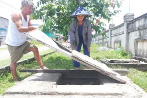 Người dân ở khu tái định cư thôn 1, 2 Tân Phúc Thành dùng tôn che tạm các hố ga sâu