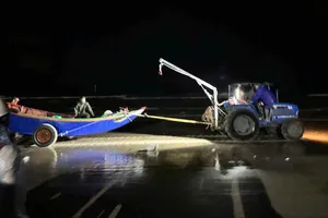 Chính quyền, lực lượng chức năng và người dân kéo dắt thuyền cá và ngư dân gặp nạn vào bờ tại thôn Phú Hải, xã Kỳ Anh