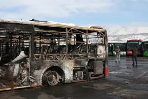 Các phóng viên truyền thông đang tác nghiệp bên cạnh một chiếc xe buýt bị phá hủy trong cuộc bạo loạn gần đây ở Tehran, Iran, ngày 21-1. Ảnh: THX