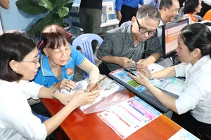 Cán bộ tổ địa bàn số phường Bình Quới hướng dẫn người cao tuổi sử dụng các ứng dụng trên điện thoại di động ngay tại khu dân cư (ẢNH: THÁI PHƯƠNG)
