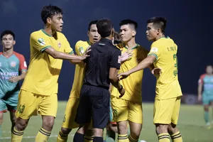 Các cầu thủ Quảng Nam vây lấy trọng tài Trần Văn Khoẻ vì bị thổi phạt đền. ẢNH: DŨNG PHƯƠNG