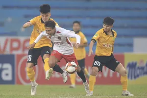 Các cầu thủ Hòa Bình (áo vàng) đầy vất vả ở trận đấu gặp đội khách Long An. ẢNH: MINH HOÀNG 