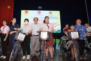 温陵会馆理事长洪世真、胡志明市各民族文学艺术协会主席张四妹向贫困学生赠送自行车。图：心雨