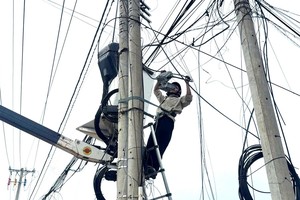 在隆海乡多条道路上，红土电力公司工作人员与各电信企业员工联合开展通信电缆整理行动，对架空电缆进行捆扎归整。图：成辉
