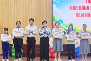 坊党委书记张明娇，坊越南祖国阵线委员会主席阮廷贵颁发奖助学金给越、华贫困学生。图：心雨