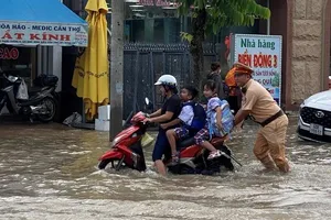 Một học sinh phụ giúp đẩy xe vượt qua triều cường