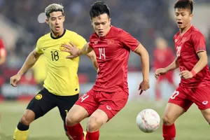 Tuyển thủ Hoàng Đức (số 14) tranh chấp bóng với cầu thủ đội tuyển Malaysia trong một trận đấu. Ảnh: Thanh Quốc