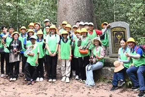 Các em học sinh chụp ảnh trước cây Vên Vên - một trong hai cây Di sản Việt Nam ở Vườn quốc gia Lò Gò - Xa Mát