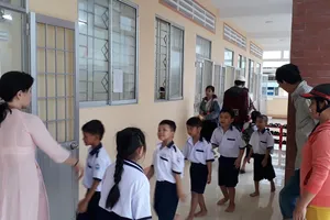 Giáo viên Trường Tiểu học Văn Lang (phường An Xuyên, tỉnh Cà Mau) hướng dẫn học sinh vào lớp học. Ảnh: TẤN THÁI