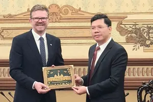 Phó Chủ tịch UBND TPHCM Hoàng Nguyên Dinh trao quà lưu niệm tặng Bộ trưởng Bộ Phát triển bang Nam Australia Chris Picton. Ảnh: THỤY VŨ