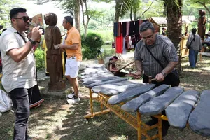 Du khách trải nghiệm chơi nhạc cụ đá tại Làng Văn hóa - Du lịch các dân tộc Việt Nam. Ảnh: THU LÊ