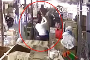 Đối tượng Hùng cầm cây gỗ dài hơn 1m đánh tới tấp vào vùng đầu, người của bà Q. Ảnh chụp từ clip